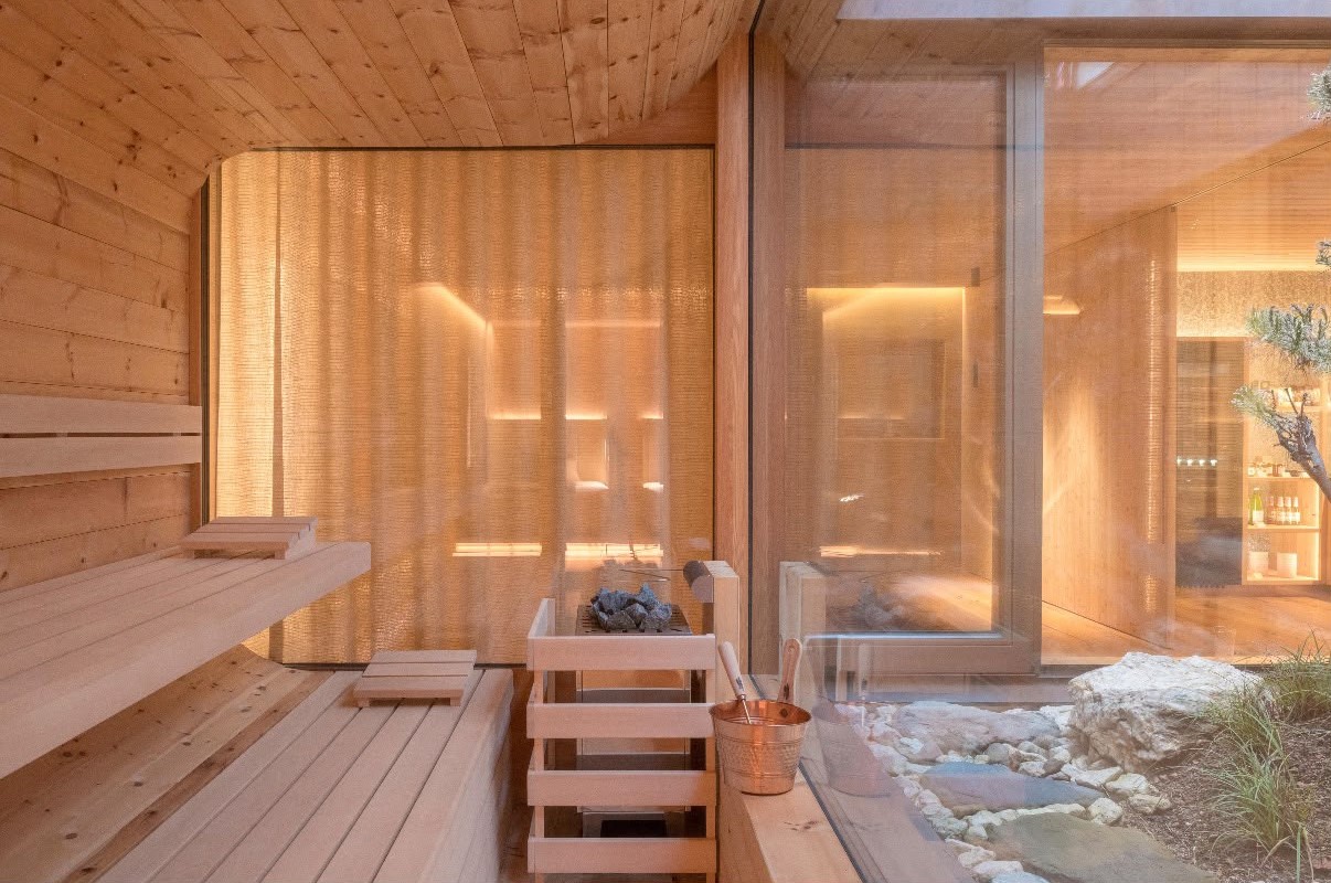 Warm wooden sauna interior with glass wall overlooking a rock garden
